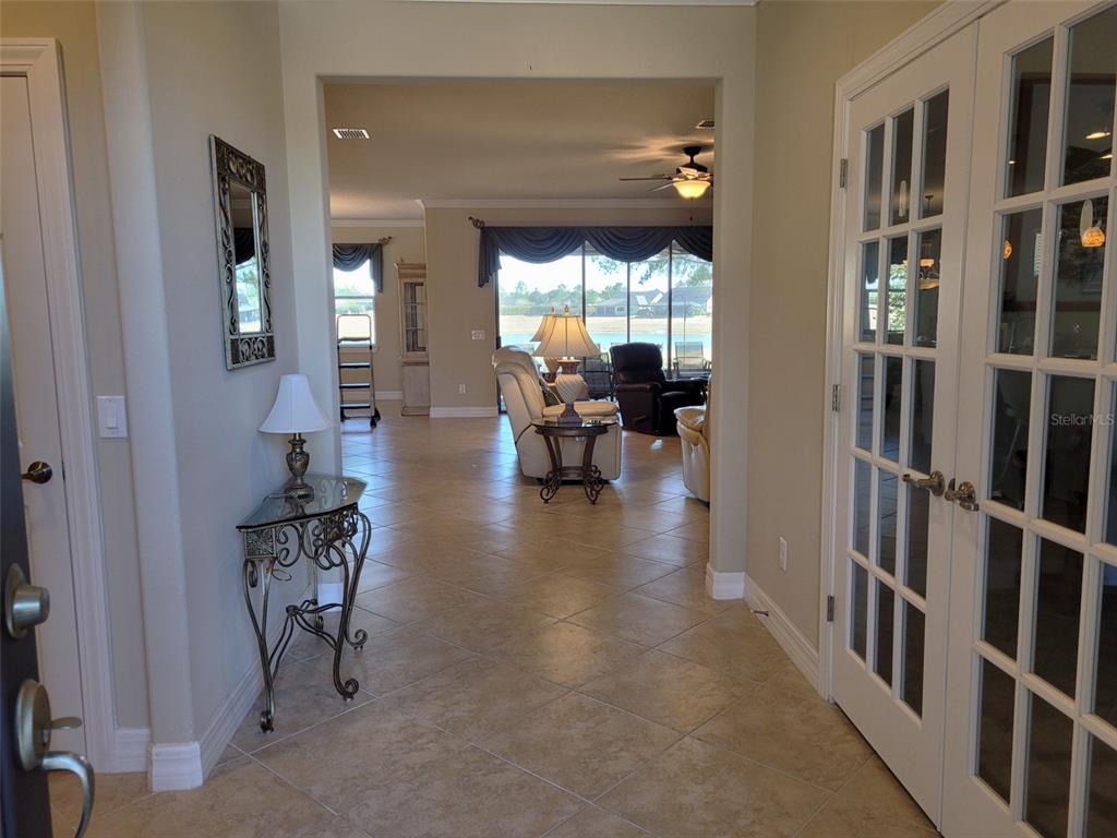 The rear exterior of a tan house features a screened-in patio and a grassy yard — 6443 SW 97TH TERRACE ROAD, OCALA, FL