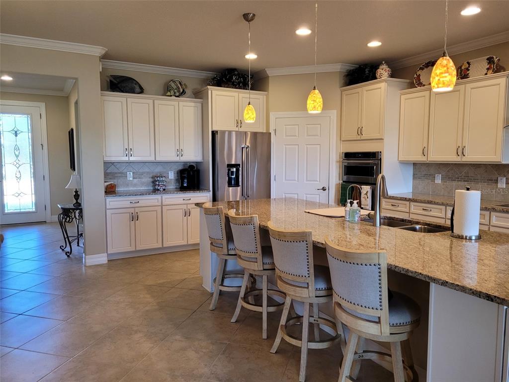An entryway with tile flooring leads into a living room featuring a view of water — 6443 SW 97TH TERRACE ROAD, OCALA, FL