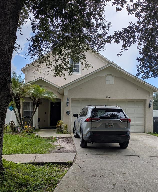 A two-story suburban house with a beige stucco exterior and a silver SUV parked outside — 11731 MANGO CROSS COURT, SEFFNER, FL