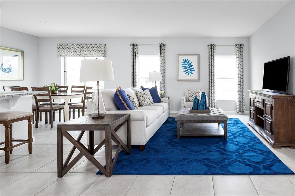 A living room and dining area feature tile floors, a blue rug, and neutral furniture — 7682 SE 114TH STREET, BELLEVIEW, FL
