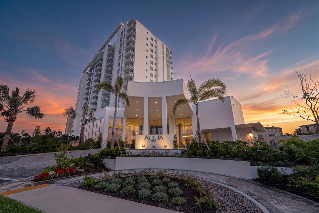A modern high-rise building with an Aqua sign stands under a colorful sunset sky — 5713 BOWEN DANIEL DRIVE UNIT 402, TAMPA, FL
