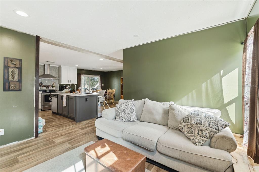 A living room with green walls and a sofa opens into a kitchen with an island — 231 TROPIC AVENUE, SATSUMA, FL