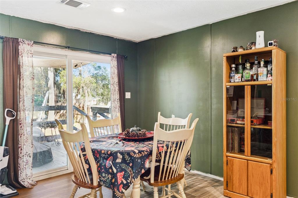 A dining room features dark green walls, a wooden hutch, and a sliding glass door — 231 TROPIC AVENUE, SATSUMA, FL