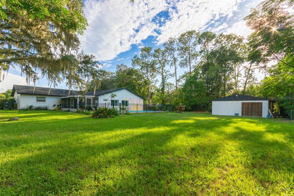 A backyard view of a white house with a pool and a detached garage — 12231 KELLY LANE, THONOTOSASSA, FL