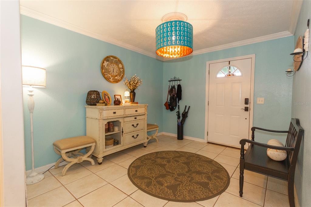 An entryway features light blue walls, tile flooring, a white cabinet, and a patterned area rug — 12231 KELLY LANE, THONOTOSASSA, FL