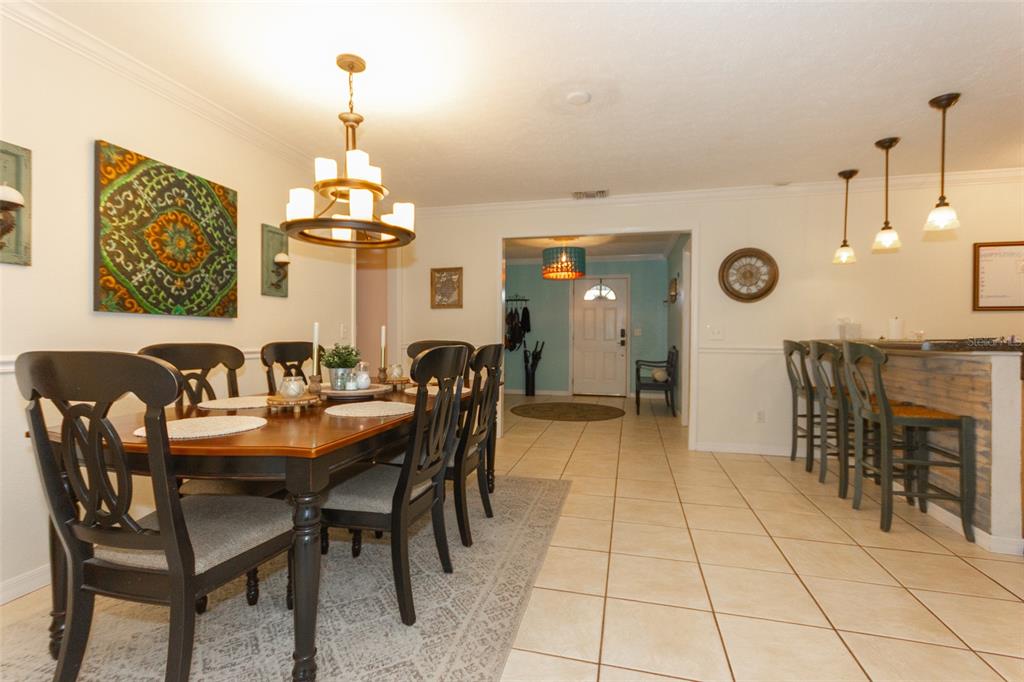 A dining room with a wooden table and chairs leads to an entryway with tile flooring — 12231 KELLY LANE, THONOTOSASSA, FL
