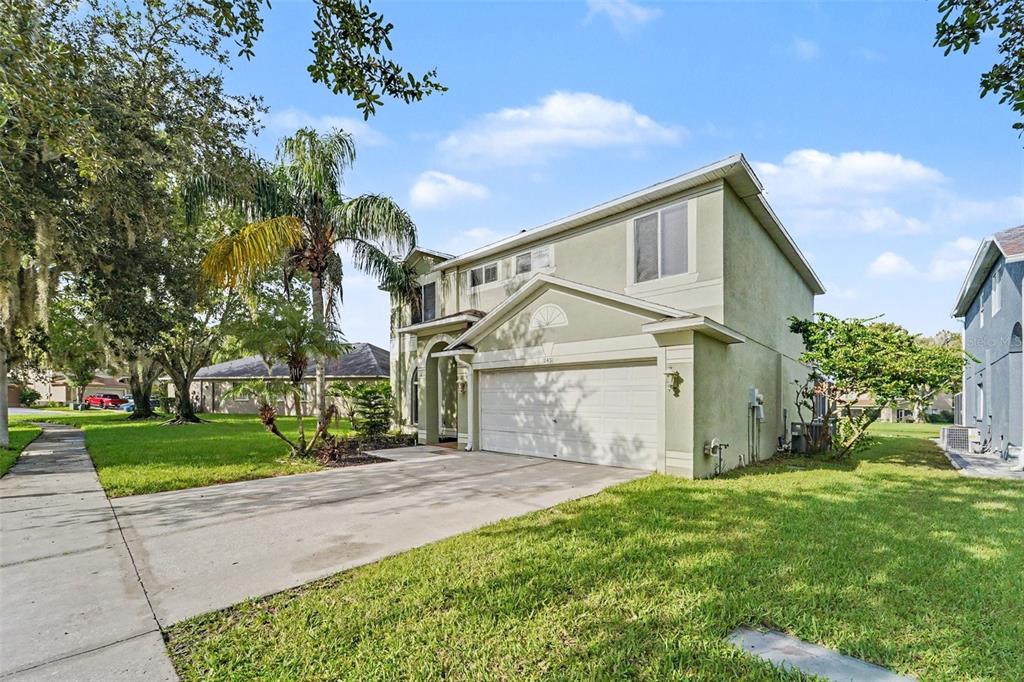 A two-story house with a light green exterior, a two-car garage, and a concrete driveway — 19431 SANDY SPRINGS CIRCLE, LUTZ, FL