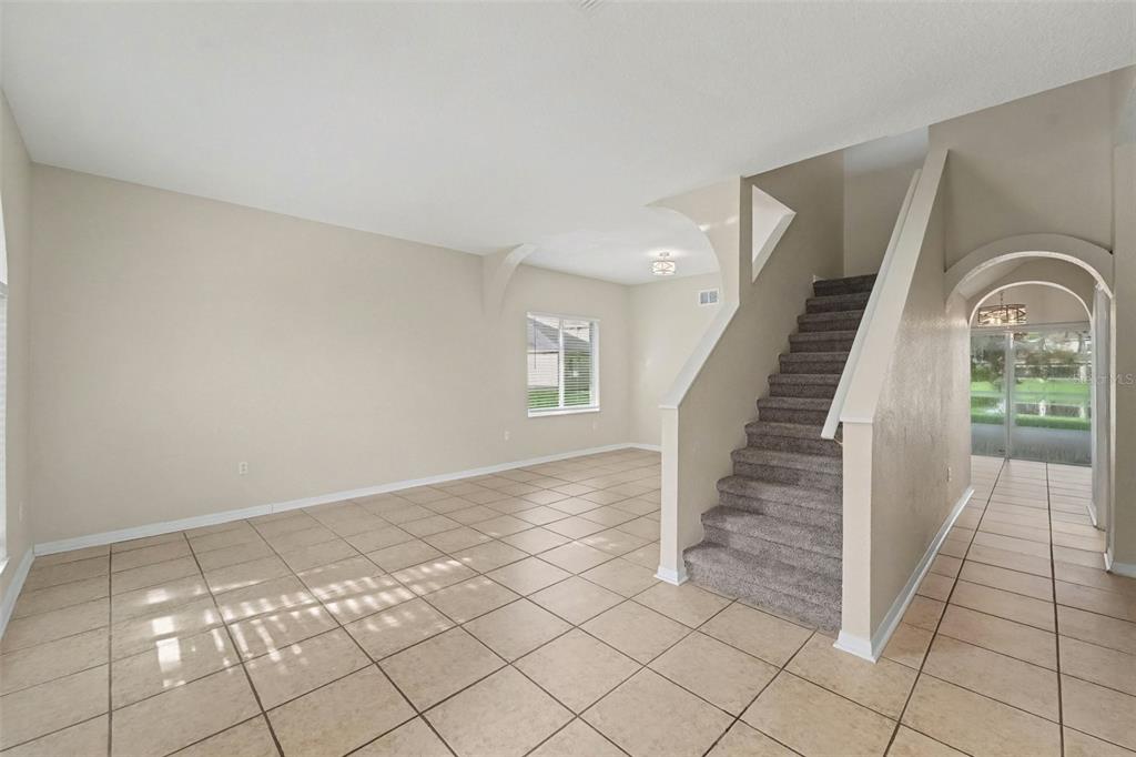 An interior view shows a tiled living area with a carpeted staircase and arched entryway — 19431 SANDY SPRINGS CIRCLE, LUTZ, FL