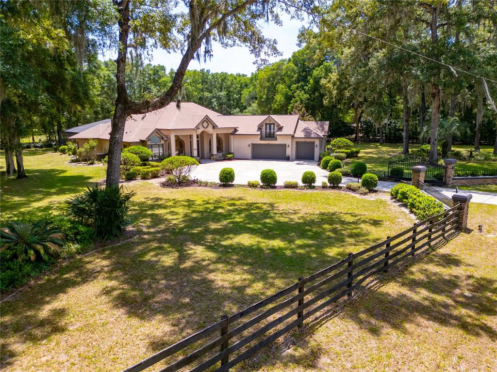 A gated driveway leads to a single-story house with a stone-accented entrance and roof gables — 1640 SE 91ST PLACE, OCALA, FL