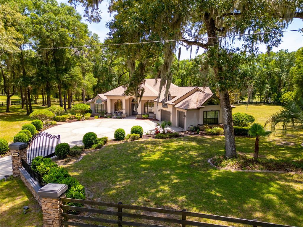 A single-story house with a beige stucco exterior, a large concrete driveway, and attached garages — 1640 SE 91ST PLACE, OCALA, FL