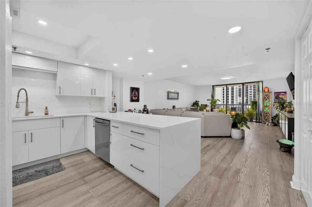 A modern white kitchen with an island and quartz countertops opens into a living area — 530 E CENTRAL BOULEVARD UNIT 803, ORLANDO, FL