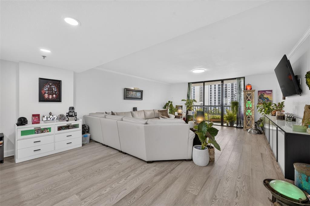 A living room features a large sectional sofa, light wood flooring, and a balcony view — 530 E CENTRAL BOULEVARD UNIT 803, ORLANDO, FL