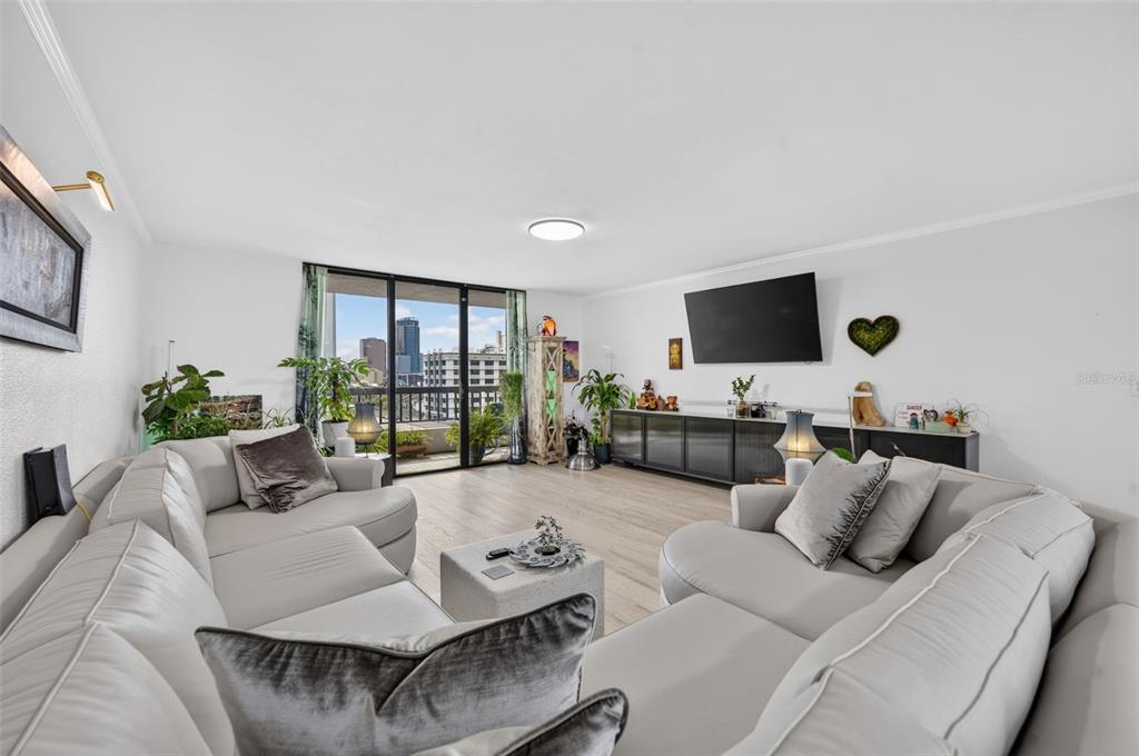 A living room features a large sectional sofa, a television, and a balcony with city views — 530 E CENTRAL BOULEVARD UNIT 803, ORLANDO, FL