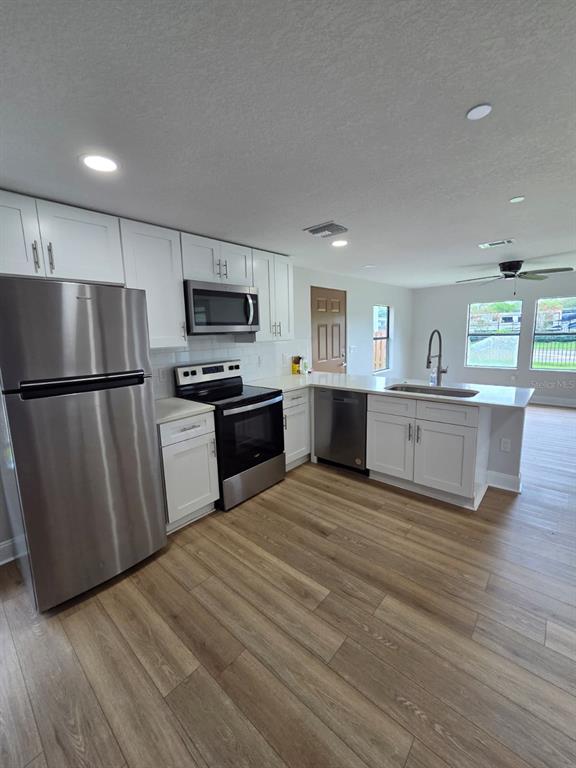 A kitchen with white cabinets, stainless steel appliances, and wood-look flooring — 300 ERON WAY UNIT 1, WINTER GARDEN, FL