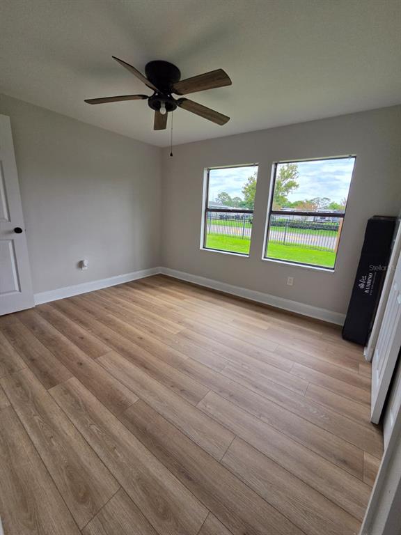 An empty bedroom features light wood-look flooring, a ceiling fan, and two windows — 300 ERON WAY UNIT 1, WINTER GARDEN, FL
