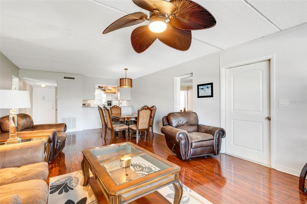 A living room and dining area with hardwood floors, brown leather furniture, and a ceiling fan — 12760 INDIAN ROCKS ROAD UNIT 119, LARGO, FL