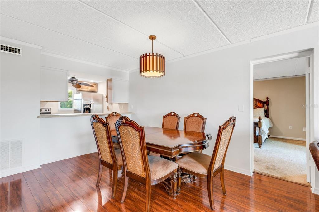 A dining area with a wooden table and chairs sits beneath a slatted pendant light — 12760 INDIAN ROCKS ROAD UNIT 119, LARGO, FL