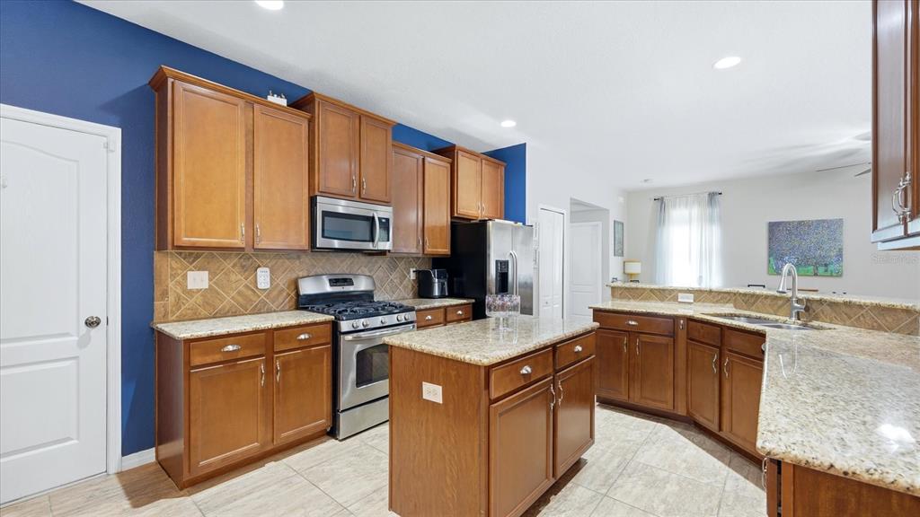 An open-concept living room and kitchen feature hardwood floors, a gray sectional, and blue walls — 5666 AARON COURT, SARASOTA, FL