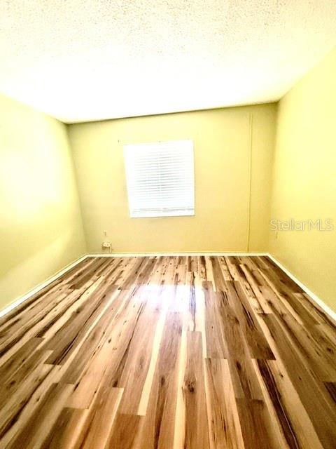 An empty room features light-colored walls, wood-look flooring, and a sliding glass door — 4111 HERON WAY UNIT E-103, BRADENTON, FL