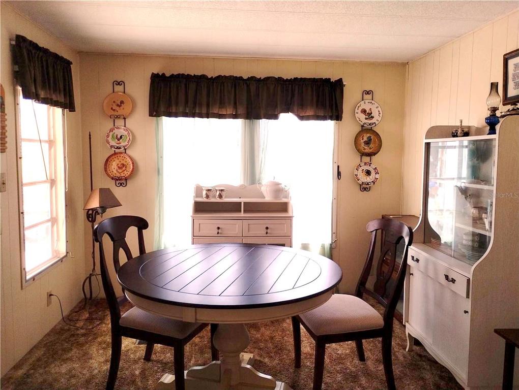 A dining room features a round dark wood table, two chairs, and decorative wall plates — 7409 SKYLINE DRIVE, HUDSON, FL