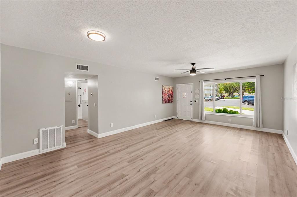 An empty living room features light wood-look flooring, gray walls, and a large front window — 2262 SWEDISH DRIVE UNIT 14, CLEARWATER, FL