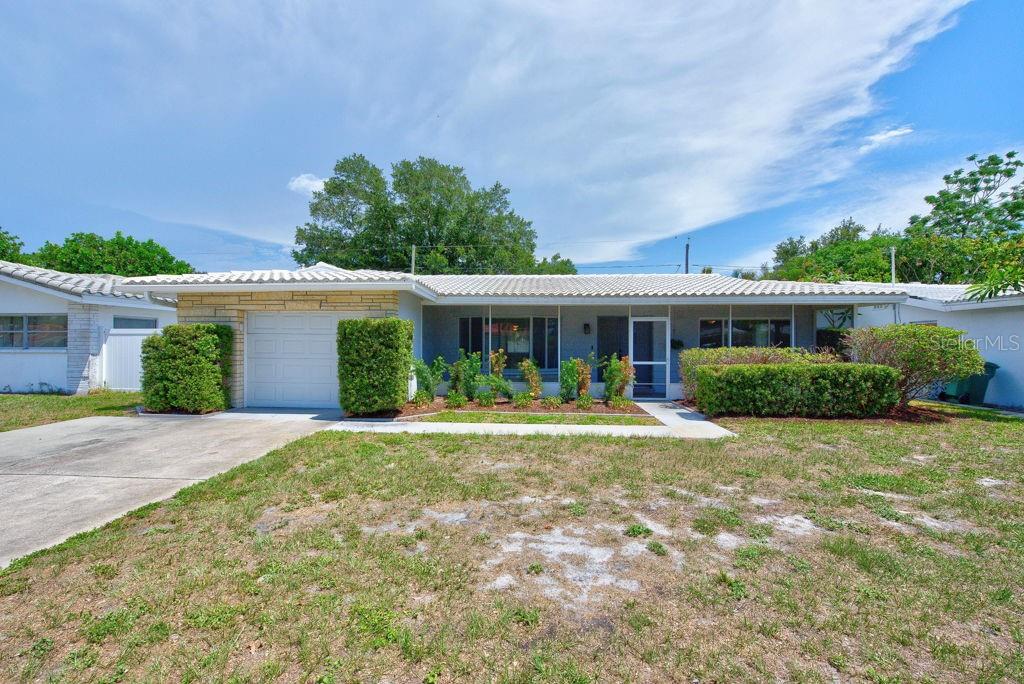 A single-story house with a white tiled roof, stone accents, and a front-facing garage — 2159 GREENBRIAR BOULEVARD, CLEARWATER, FL