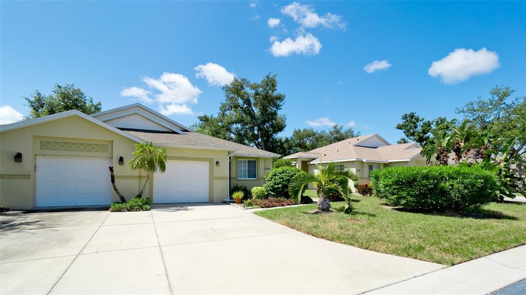 A light-colored house with a two-car garage and a paved driveway under a blue sky — 209 28TH STREET W, PALMETTO, FL