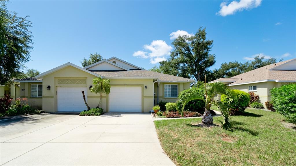 A single-story house with a two-car garage, a concrete driveway, and a palm tree — 209 28TH STREET W, PALMETTO, FL