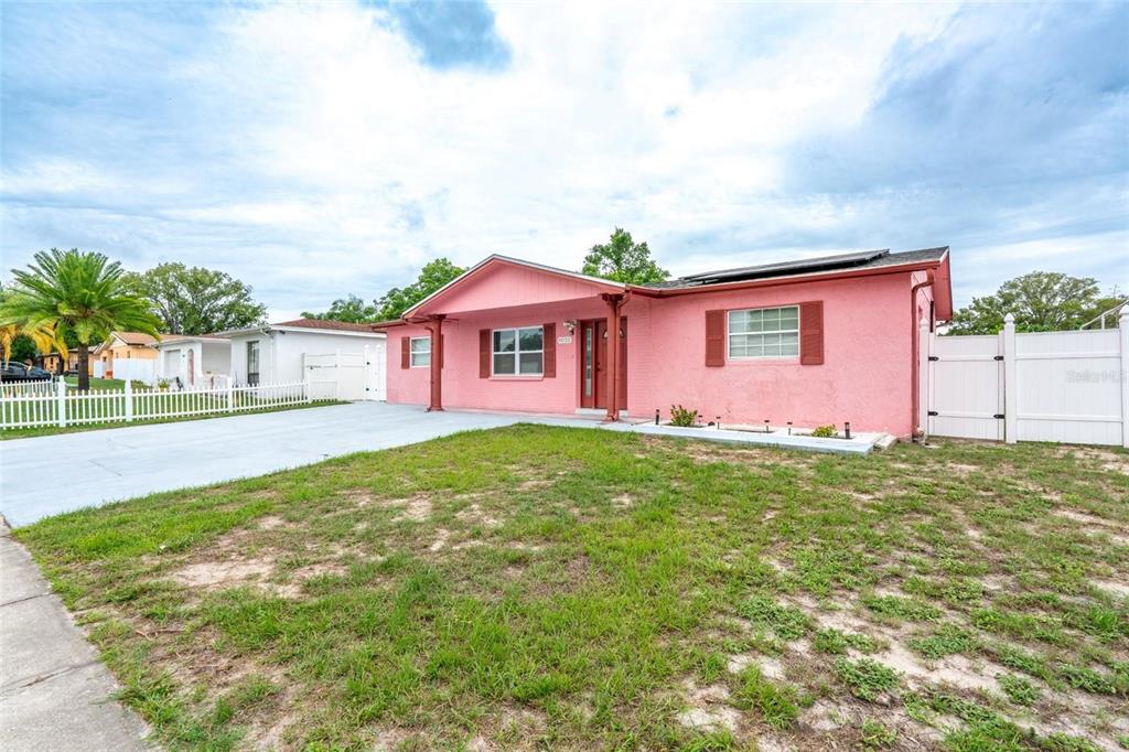 A single-story pink house with a white fence and a paved driveway — 8033 MANVEL DRIVE, PORT RICHEY, FL