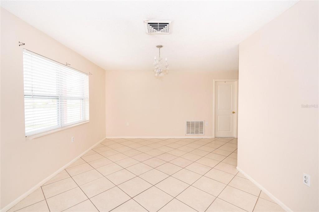 A dining room with beige walls, tile flooring, a window with blinds, and a chandelier — 8033 MANVEL DRIVE, PORT RICHEY, FL