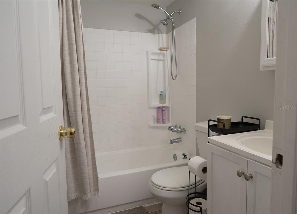 A bathroom features a white vanity, a toilet, and a shower-tub combination with white tiles — 3667 135TH AVENUE, LARGO, FL
