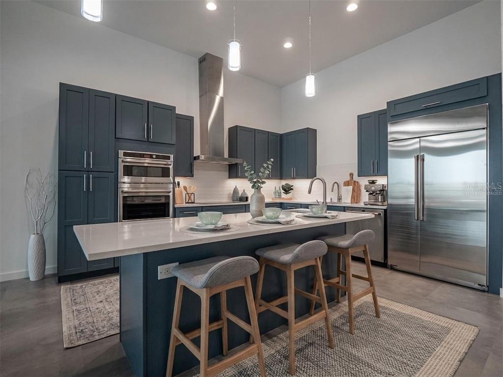 A modern kitchen features blue cabinetry, a white quartz island, and three white bar stools — 920 N OSCEOLA AVENUE UNIT 801, CLEARWATER, FL