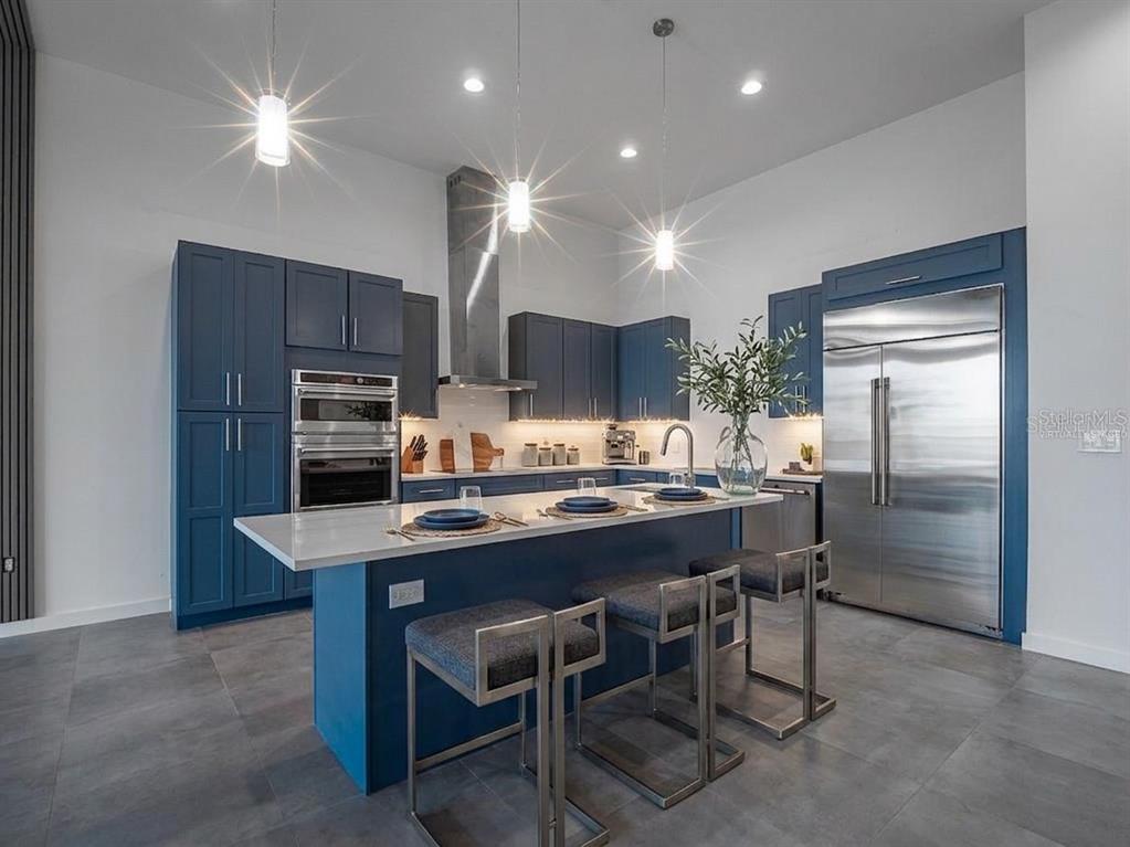 A modern kitchen features blue cabinetry, stainless steel appliances, and a large white island — 920 N OSCEOLA AVENUE UNIT 801, CLEARWATER, FL