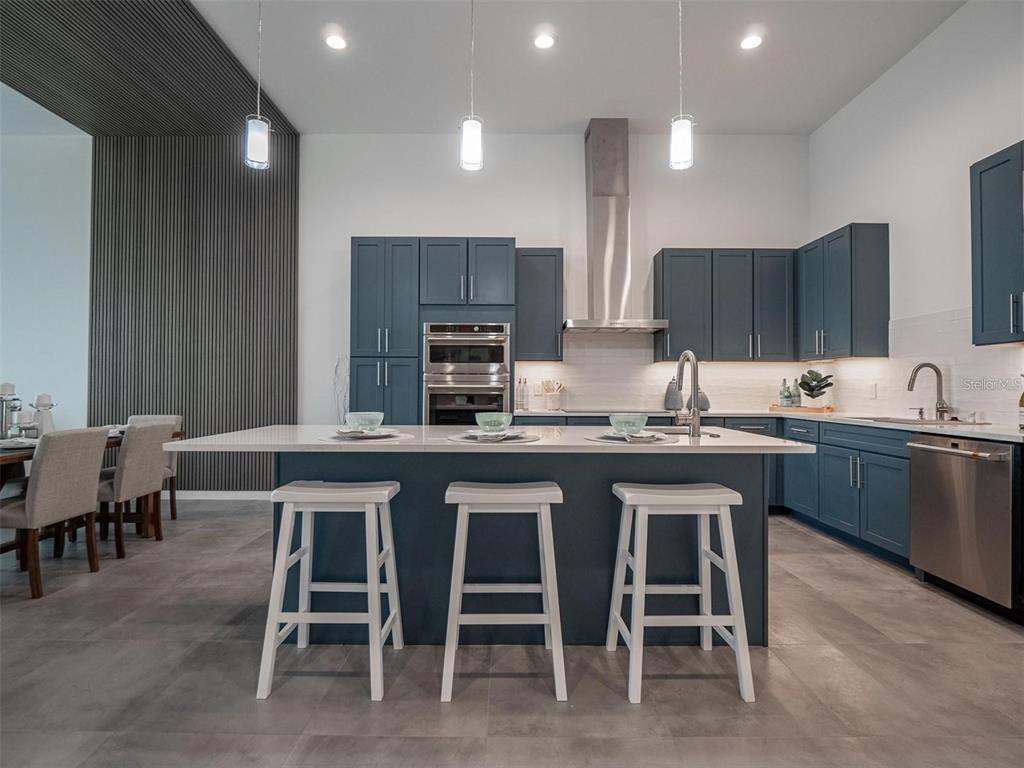 A modern kitchen features blue cabinetry, a white quartz island, and stainless steel appliances — 920 N OSCEOLA AVENUE UNIT 801, CLEARWATER, FL