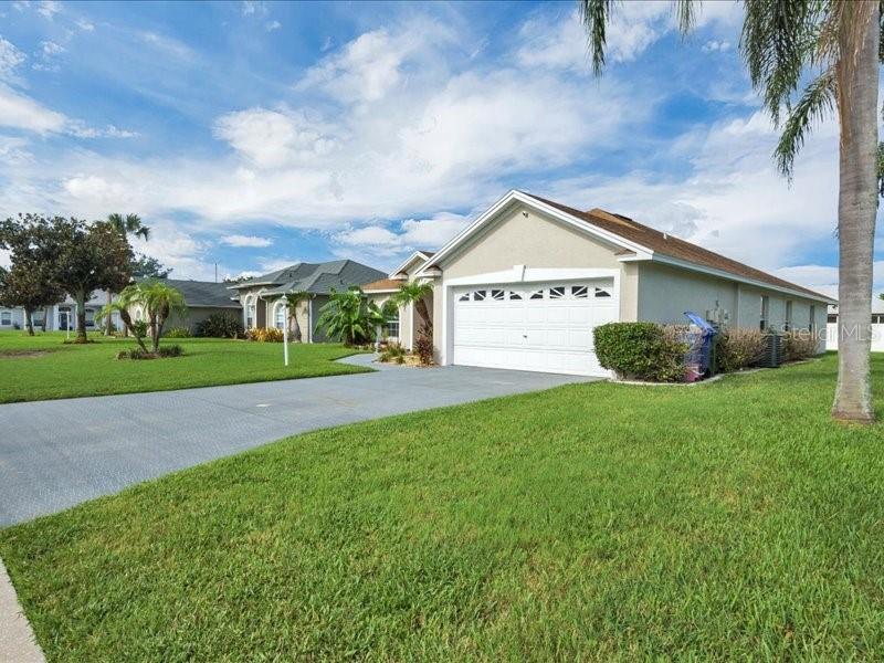 A beige single-story house with a two-car garage and a large front lawn — 344 RUBY LAKE LOOP, WINTER HAVEN, FL