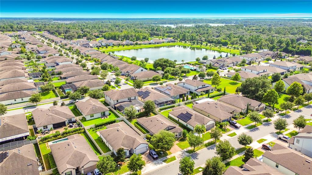 A grassy backyard features a gray stucco house exterior, a white vinyl fence, and trees — 2892 MATERA DRIVE, ST CLOUD, FL