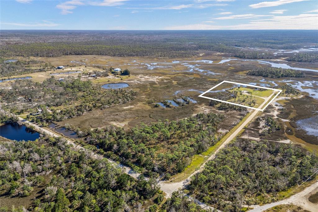 An aerial view shows a rural property outlined in white surrounded by marshland and trees — 125 SW 284, STEINHATCHEE, FL