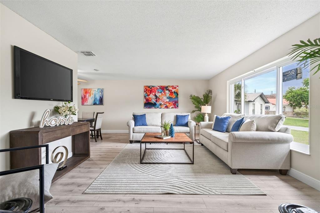A living room features light wood floors, two beige sofas, and a large area rug — 7525 LODGE POLE TRAIL, WINTER PARK, FL