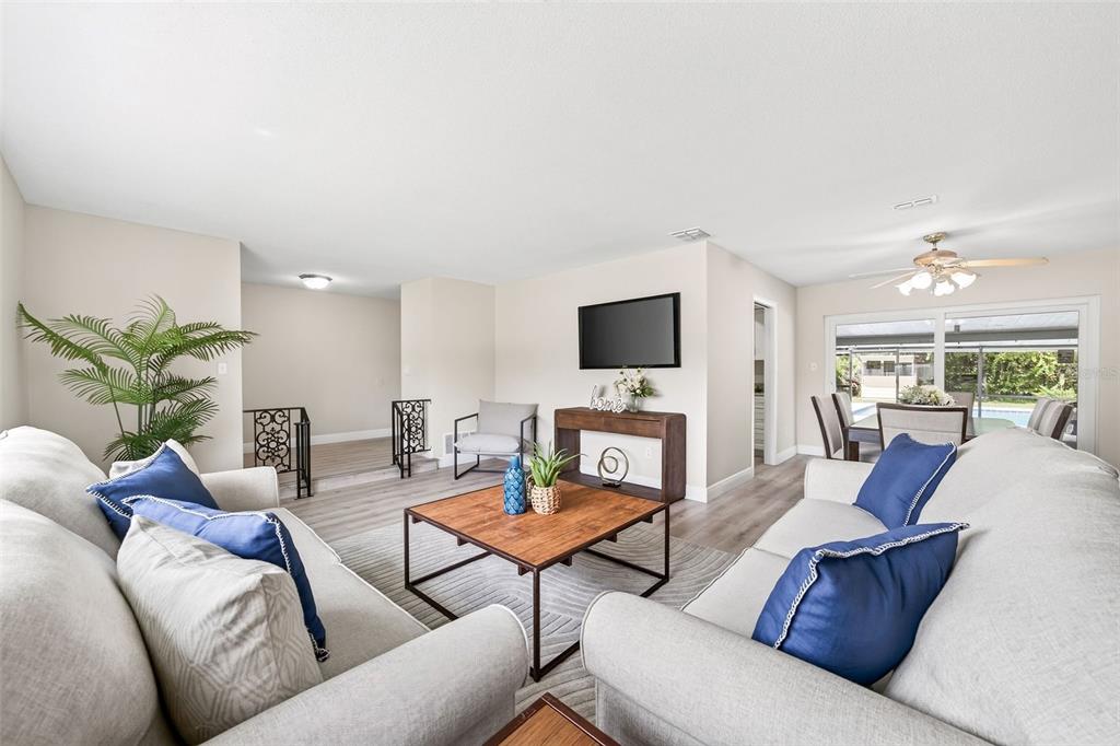 A living room with light gray flooring, two sofas, a coffee table, and a television — 7525 LODGE POLE TRAIL, WINTER PARK, FL