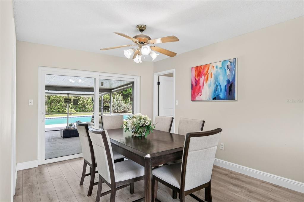 A dining room features a dark wood table, six chairs, a ceiling fan, and sliding doors — 7525 LODGE POLE TRAIL, WINTER PARK, FL
