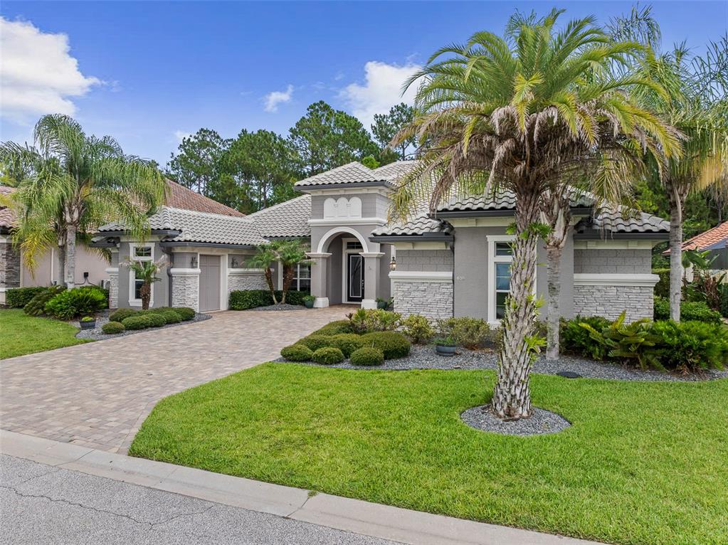 A single-story house with a gray stucco exterior, stone accents, and a paved driveway — 630 WOODBRIDGE DRIVE, ORMOND BEACH, FL