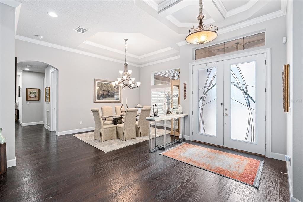 A bright foyer with dark hardwood floors leads into a dining area with a chandelier — 630 WOODBRIDGE DRIVE, ORMOND BEACH, FL