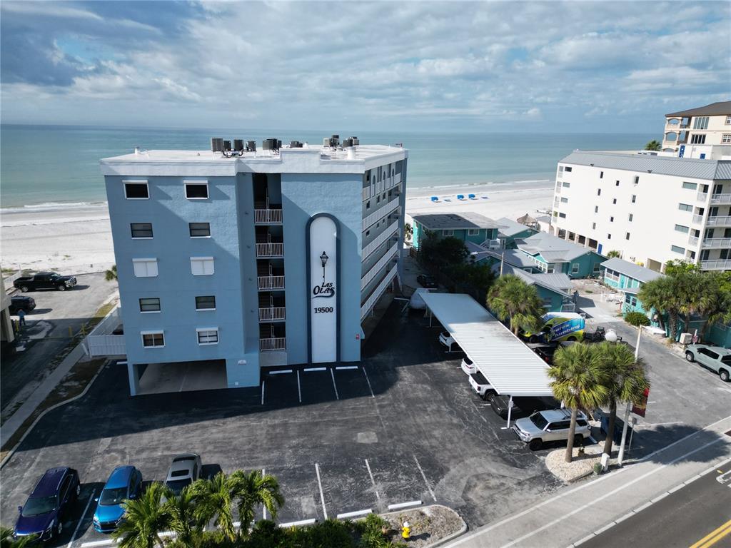 An exterior view of a blue multi-story apartment building with a parking lot — 19500 GULF BOULEVARD UNIT 102, INDIAN SHORES, FL