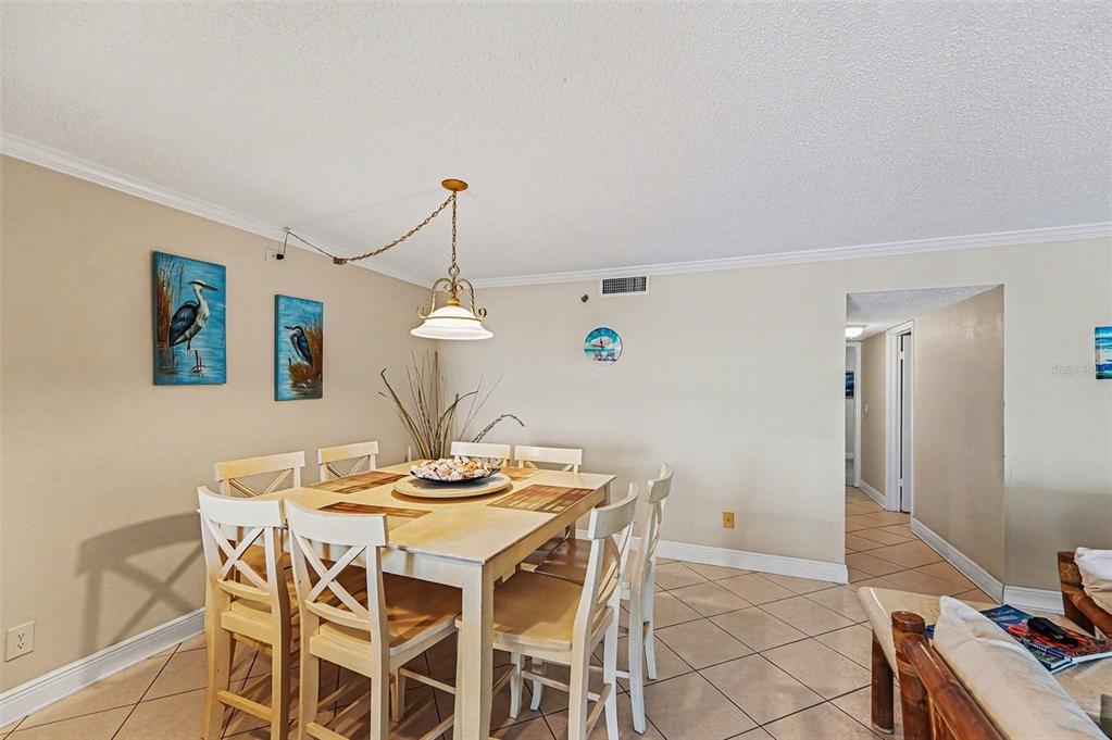 A balcony with patio furniture overlooks a swimming pool, a parking lot, and the beach — 19500 GULF BOULEVARD UNIT 102, INDIAN SHORES, FL