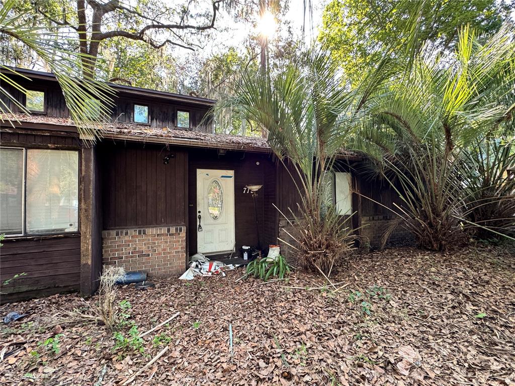 A brown wood-sided house with a brick base and a white front door — 713 NW 95TH TERRACE, GAINESVILLE, FL