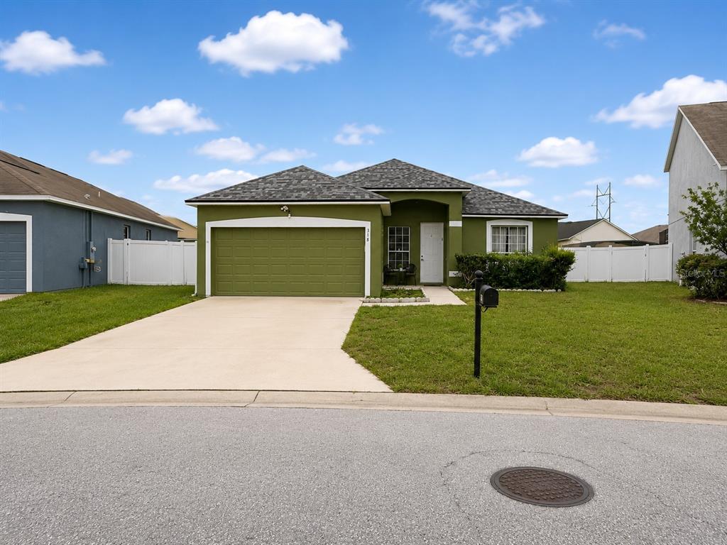 A single-story house with a green exterior, a two-car garage, and a concrete driveway — 318 SIGMUND LOOP, DAVENPORT, FL
