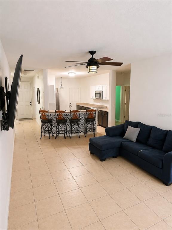 A living room with a blue sectional sofa opens to a kitchen with a breakfast bar — 318 SIGMUND LOOP, DAVENPORT, FL