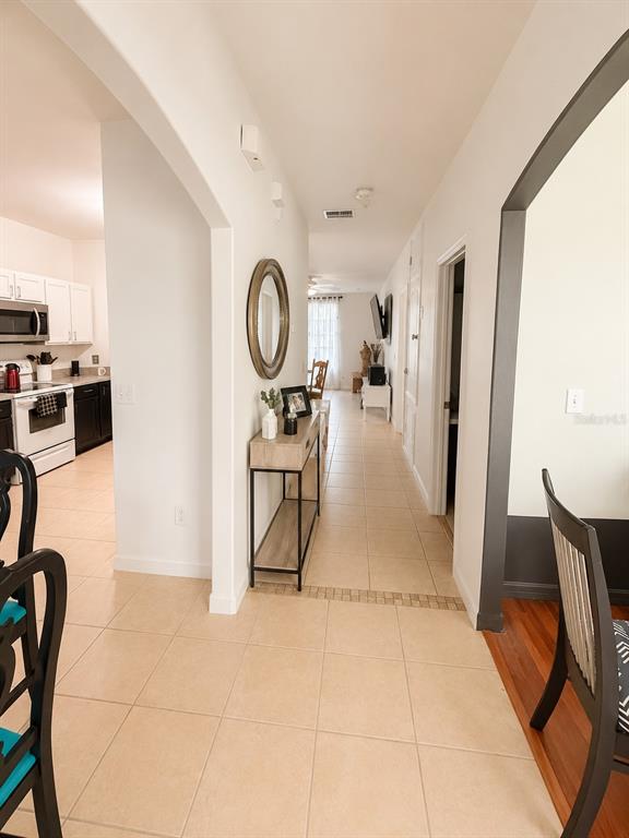 A hallway with tile flooring connects a kitchen on the left to a living area — 318 SIGMUND LOOP, DAVENPORT, FL