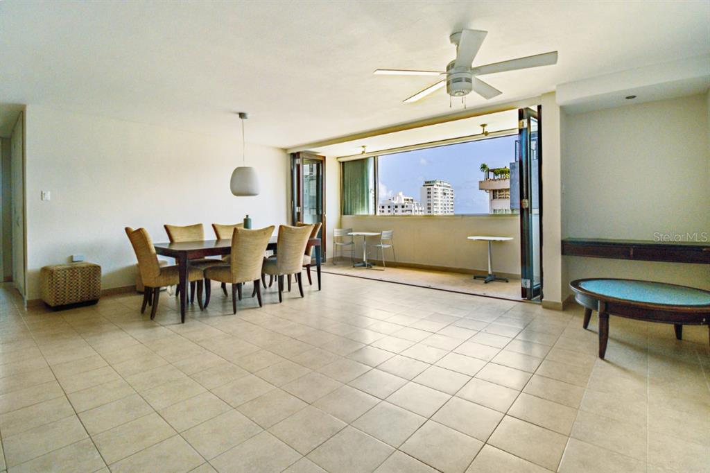 A dining area with tile floors opens to a balcony overlooking a city skyline — FULL POWER GENERATOR KINGS COURT 80 STREET UNIT 804, SAN JUAN, PR