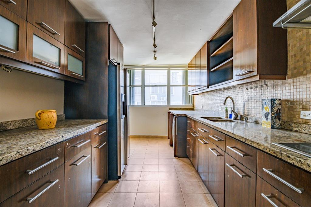 A galley kitchen features dark wood cabinets, granite countertops, and a tiled floor — FULL POWER GENERATOR KINGS COURT 80 STREET UNIT 804, SAN JUAN, PR